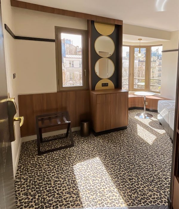 Chambre de l'hôtel Villa Luxembourg avec de la moquette effet léopard, des meubles en bois et des miroirs tout en rondeur